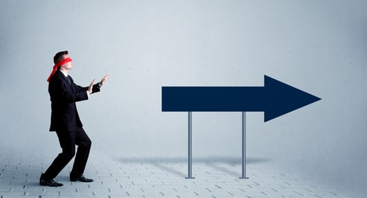 A lost young sales person with blindfolds trying to find the right path concept with large blue arrow sign pointing forward.